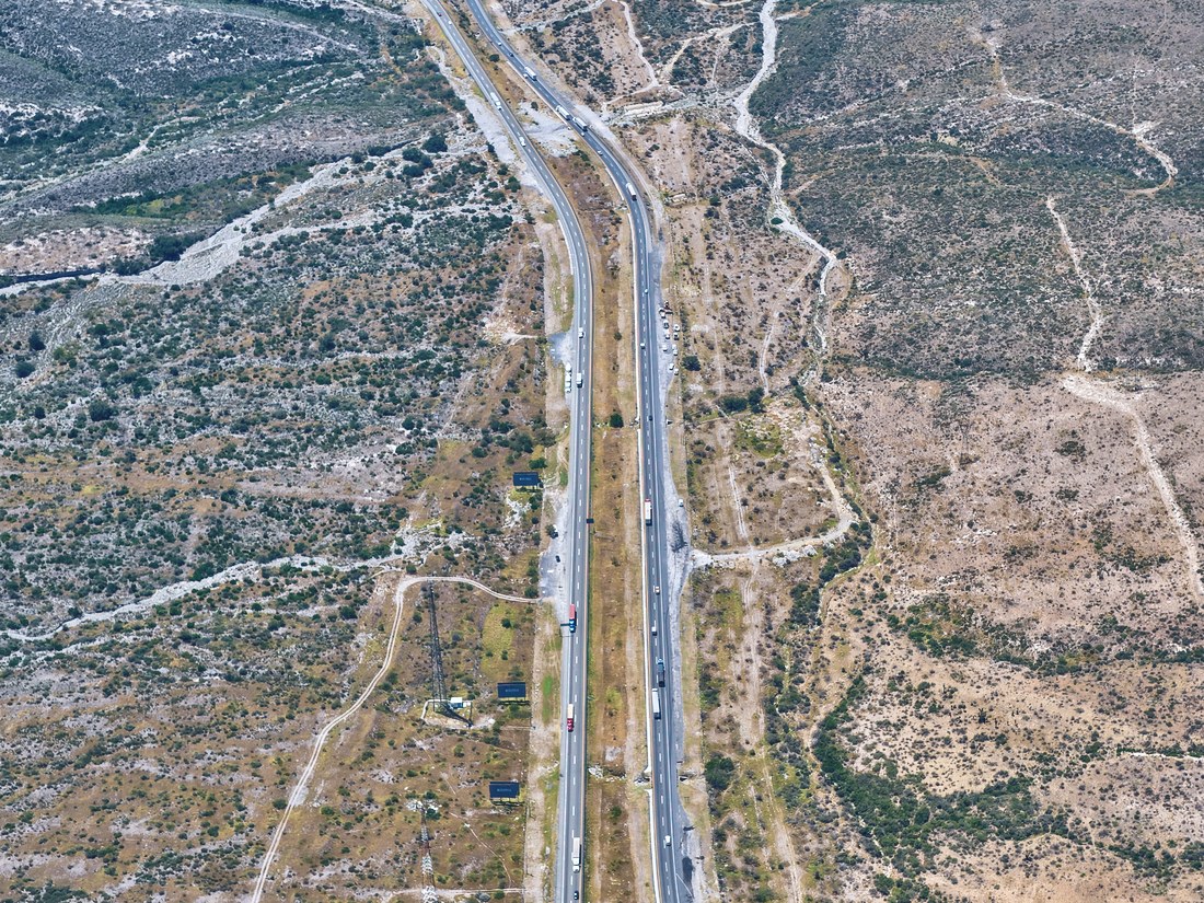 Autopista de cuerpos separados cruzando terreno agreste, vista desde el aire